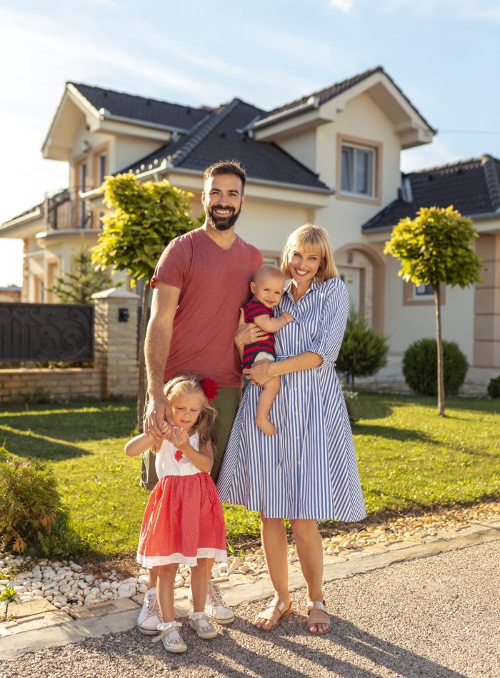 Parents and children having fun standing in front of their new house